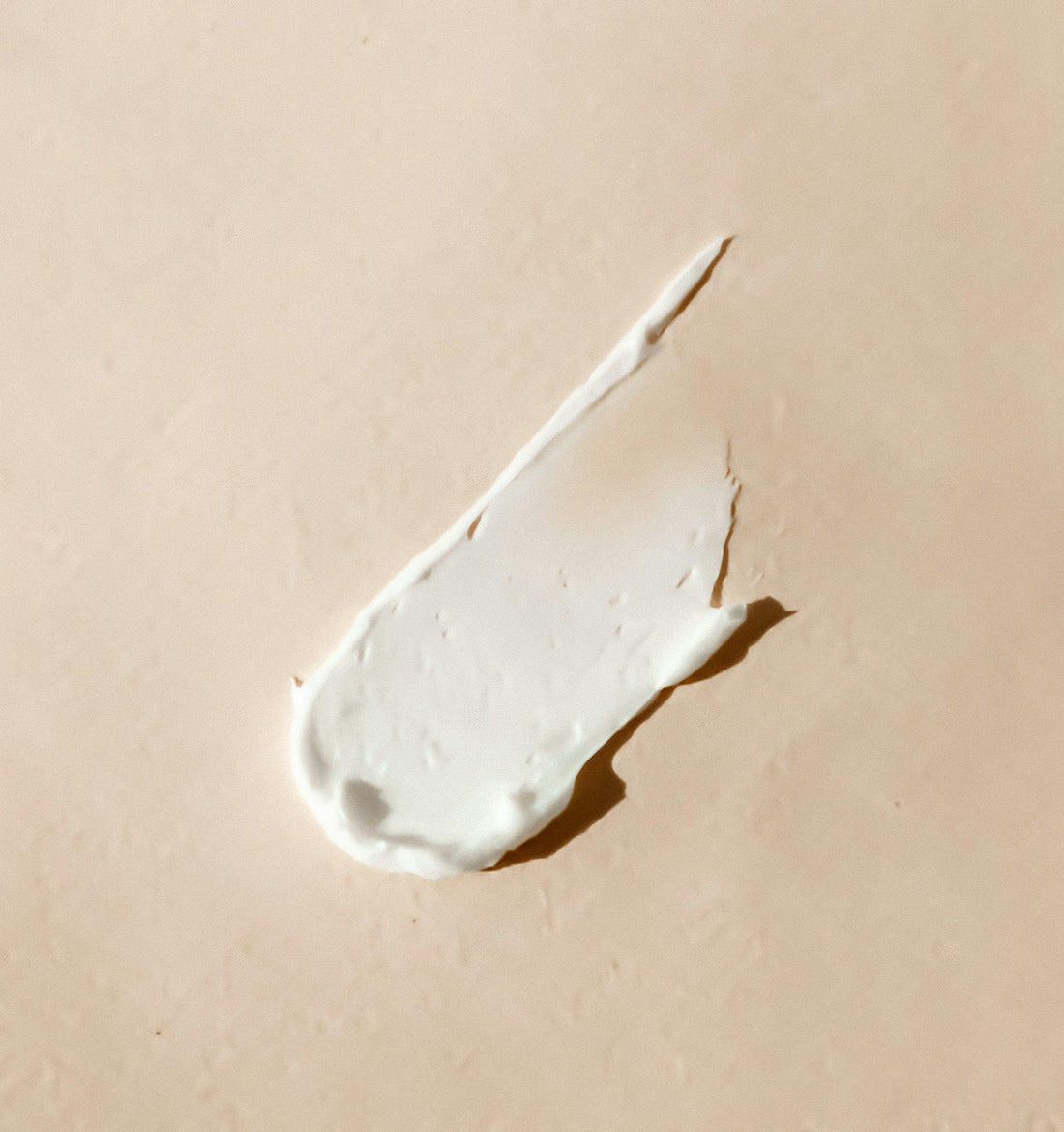 Rich moisturising cream texture on a soft beige background